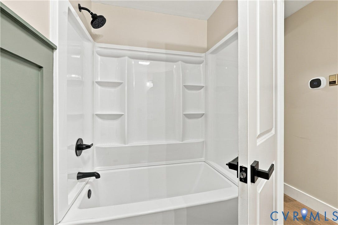 17 River Walk, Cumberland, VA 23027 Bathtub with integrated shelving, matte black fixtures, and a shower head