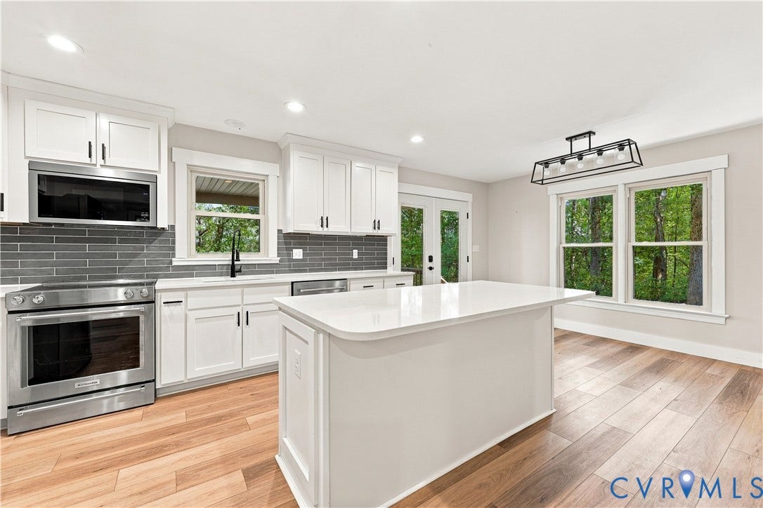17 River Walk, Cumberland, VA 23027 Kitchen with wood-finish flooring, white cabinetry, a kitchen island, stainless steel appliances, and a tiled backsplash