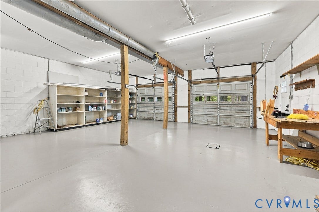 17 River Walk, Cumberland, VA 23027 Spacious garage with multiple overhead doors, built-in shelving, and a workbench
