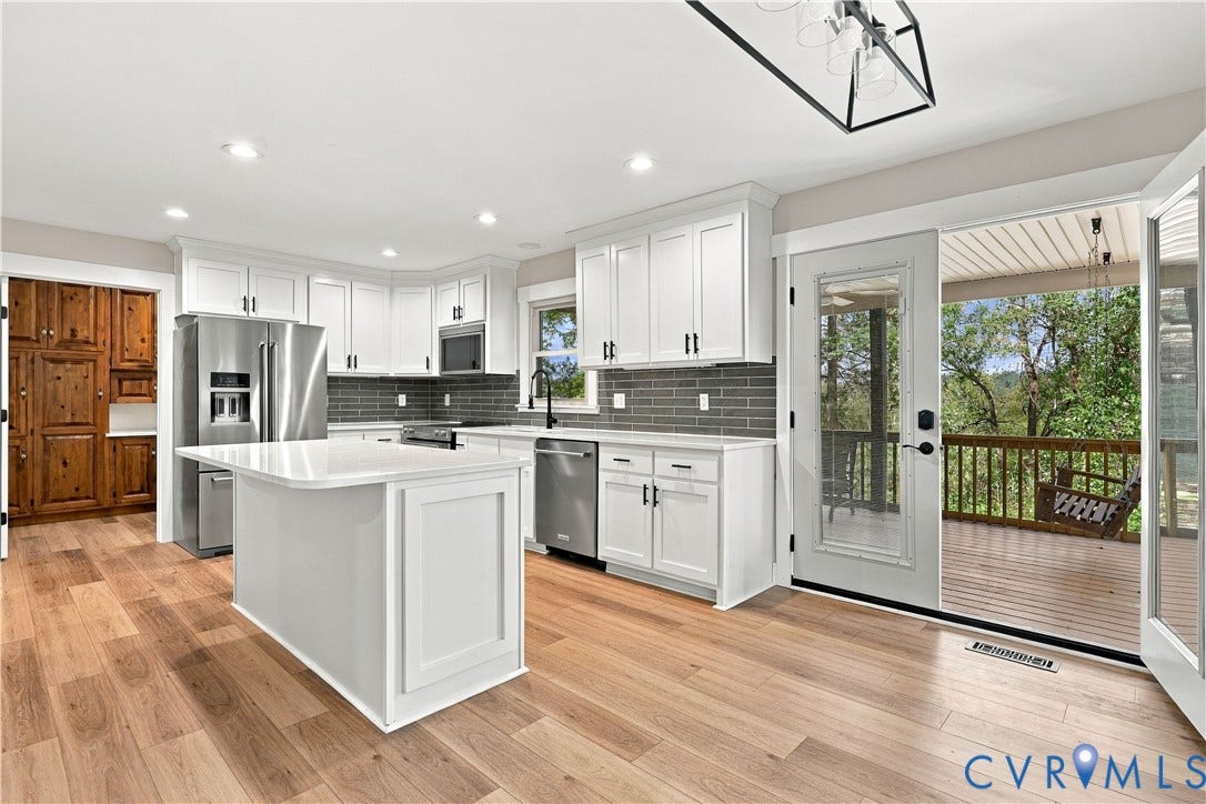 17 River Walk, Cumberland, VA 23027 Kitchen featuring light wood-finish flooring, white cabinetry, a white island with a solid surface countertop, stainless steel appliances, and gray subway tile backsplash
