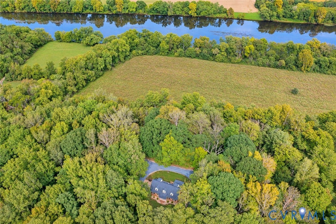 17 River Walk, Cumberland, VA 23027 Aerial property featuring a single-family home with a circular driveway, surrounded by mature trees, and bordered by a river and open fields