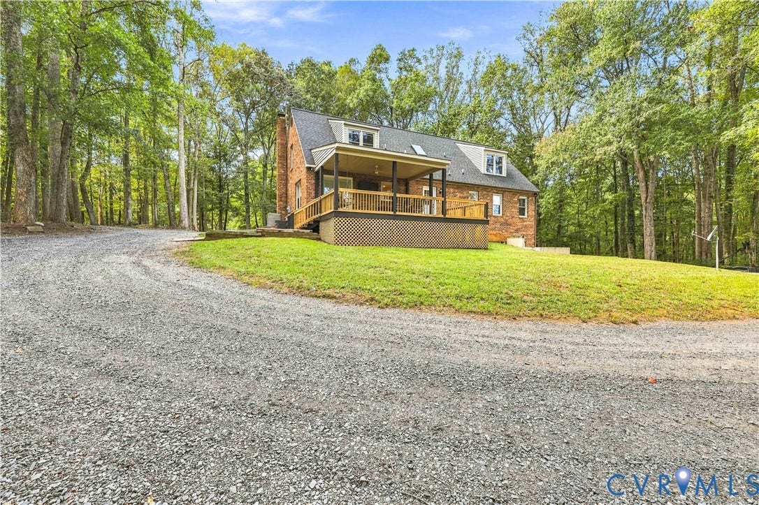 17 River Walk, Cumberland, VA 23027 Brick exterior residence with a gravel driveway, mature trees, a wood deck, and a covered porch