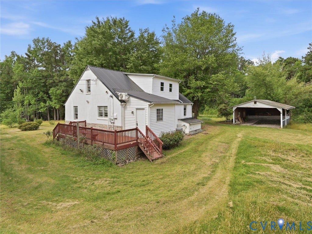 21600 Patrick Henry Highway, Amelia, VA 23083 White exterior with a black metal roof, raised wooden deck, and a detached carport structure