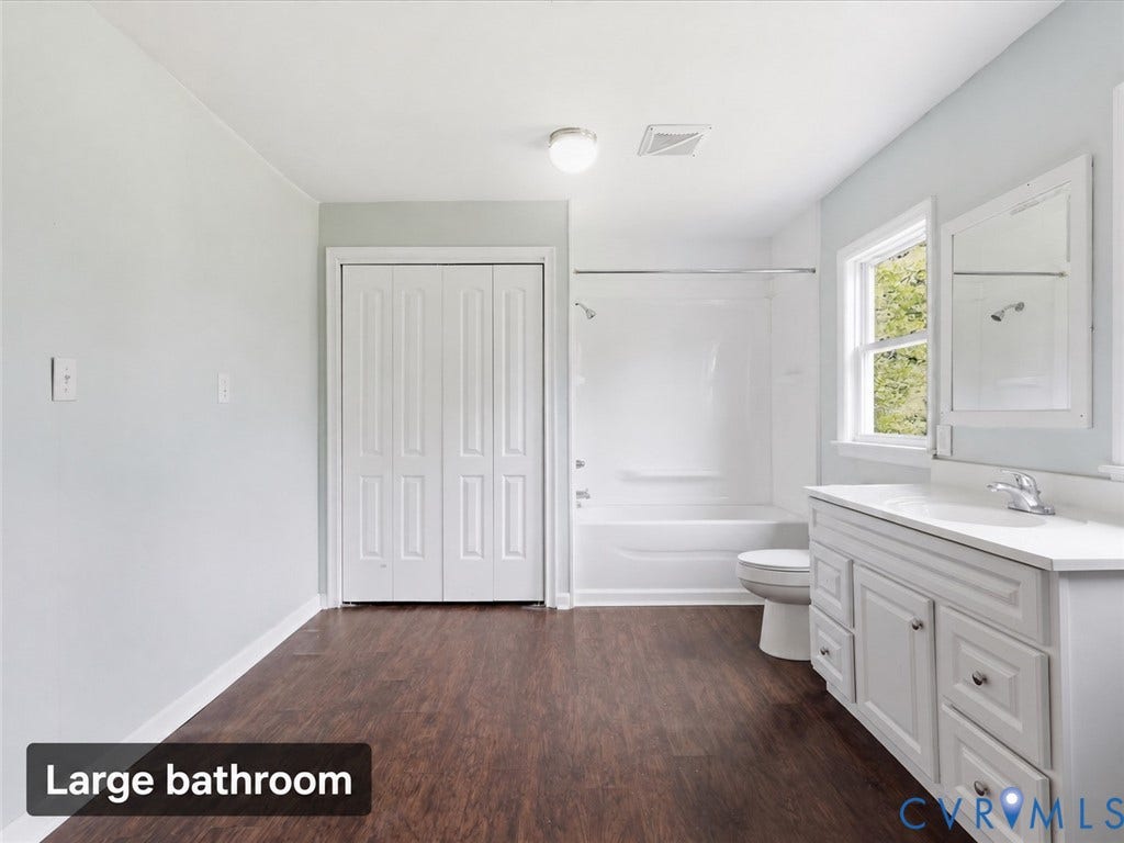 21600 Patrick Henry Highway, Amelia, VA 23083 Wood-finish flooring, white vanity with integrated sink, window, built-in bathtub with shower, and bi-fold closet doors
