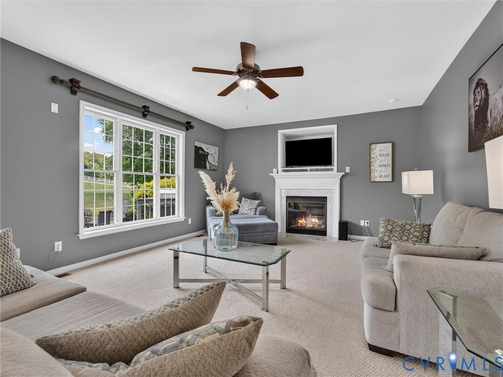 7478 Troub Lane, Elwin Place, Mechanicsville, VA 23111 Spacious living area featuring a prominent fireplace with white mantel, a ceiling fan, and large windows with white trim