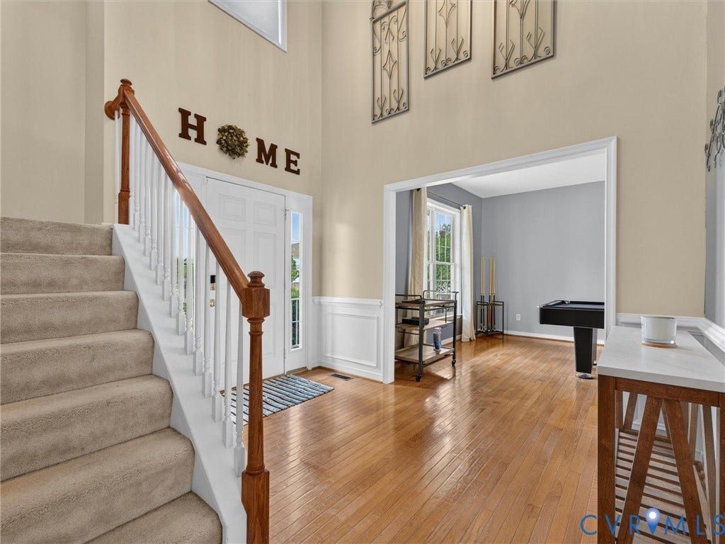 7478 Troub Lane, Elwin Place, Mechanicsville, VA 23111 Two-story entry foyer with wood-finish flooring, a carpeted staircase with wood handrail, and white paneled wainscoting