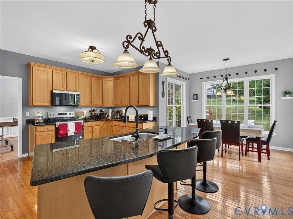 7478 Troub Lane, Elwin Place, Mechanicsville, VA 23111 Kitchen featuring light wood cabinetry, dark speckled countertops, stainless steel appliances, and a large central island with a built-in sink