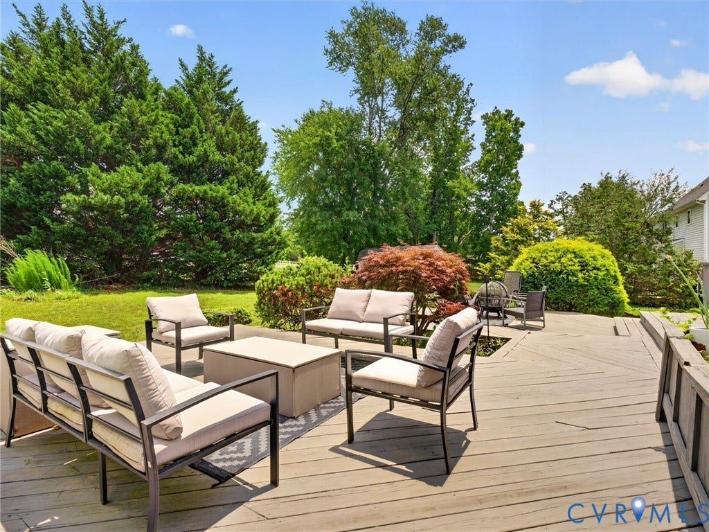 7478 Troub Lane, Elwin Place, Mechanicsville, VA 23111 Expansive outdoor decking, lush green lawn, mature trees, landscaped shrubbery, and a built-in planter