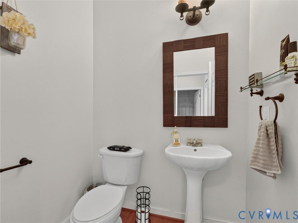 7478 Troub Lane, Elwin Place, Mechanicsville, VA 23111 Pedestal sink with an antique bronze faucet, framed mirror, and a wall-mounted light fixture