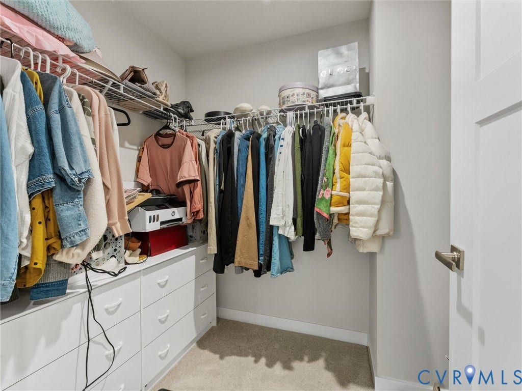 Walk-in closet featuring built-in white cabinetry, wire shelving, and carpet flooring