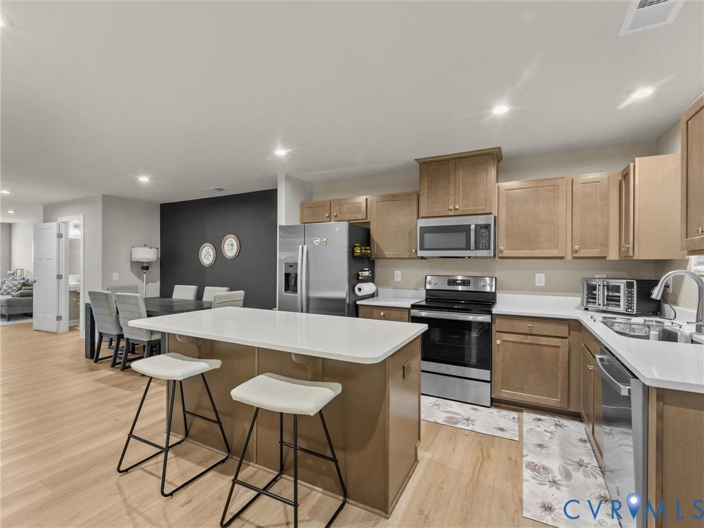 Kitchen featuring wood-finish flooring, stainless steel appliances, and a central island with white countertops