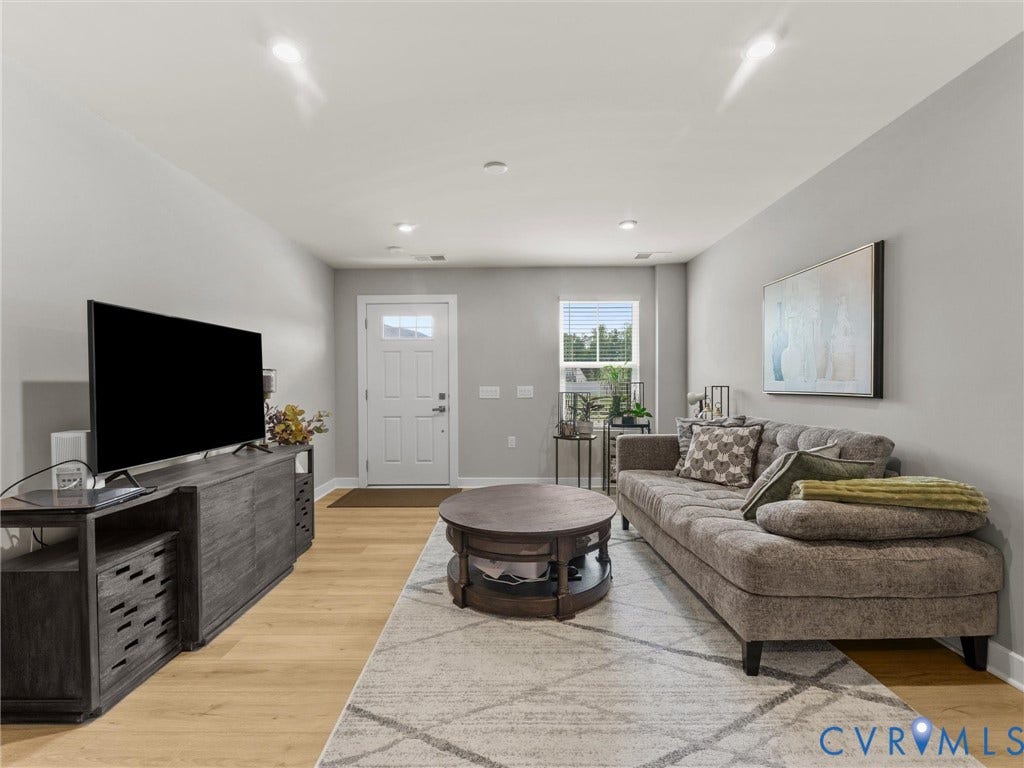 Recessed lighting, wood-finish flooring, white paneled entry door with frosted glass, and light gray wall finishes