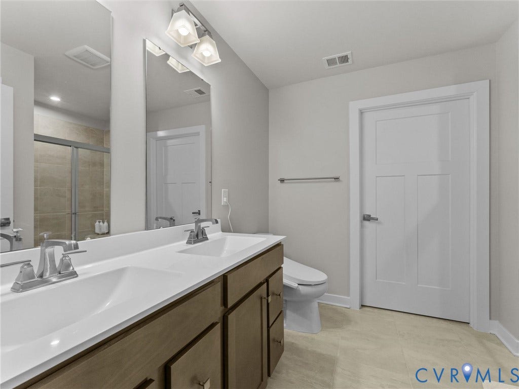 Dual vanity with integrated sinks, wood-finish cabinetry, brushed nickel fixtures, and overhead lighting
