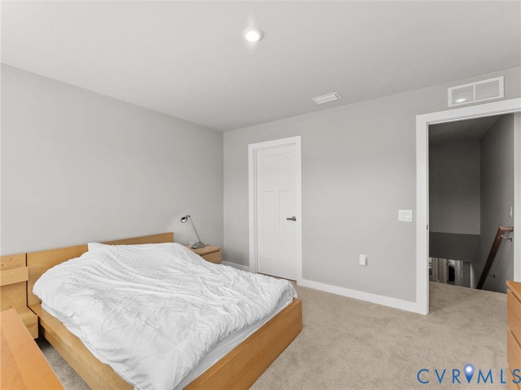 Light gray wall paint, recessed ceiling light, white trim, light-colored carpeting, and white interior door