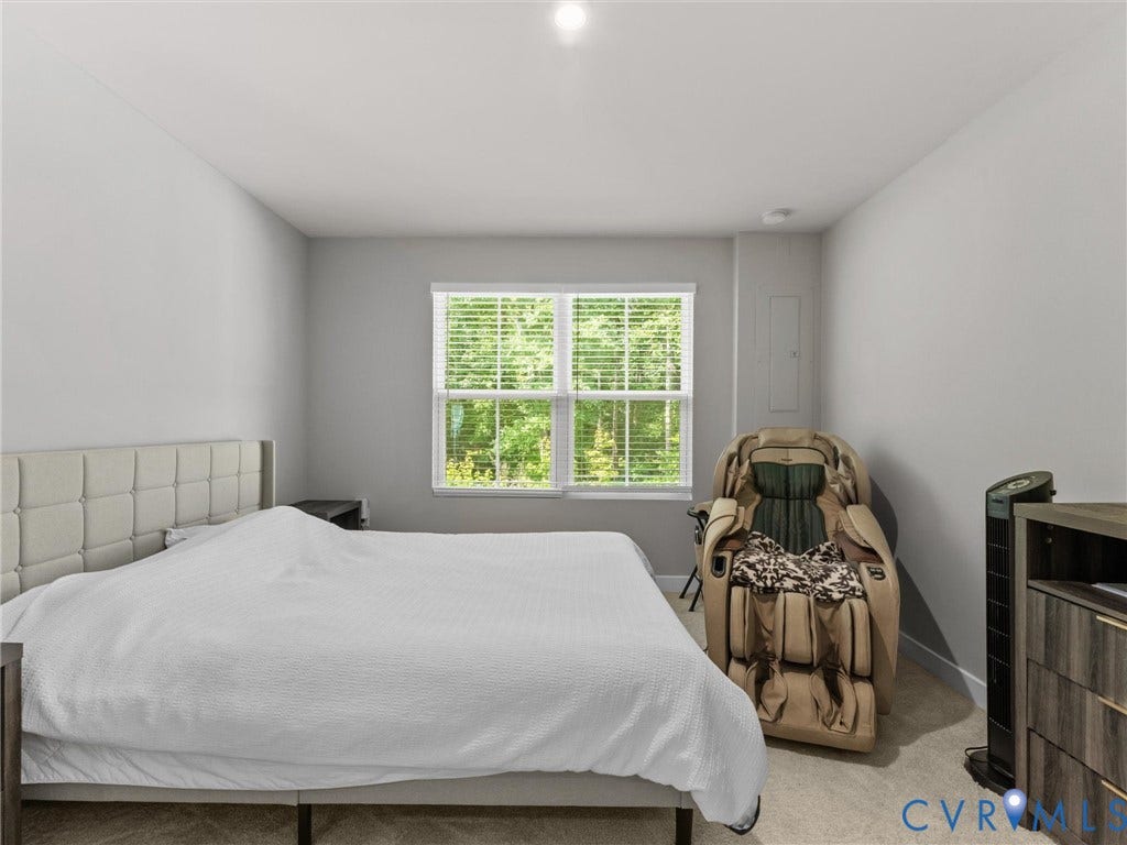 Wall-to-wall carpeting with light gray walls, a window with horizontal blinds, and a built-in access panel