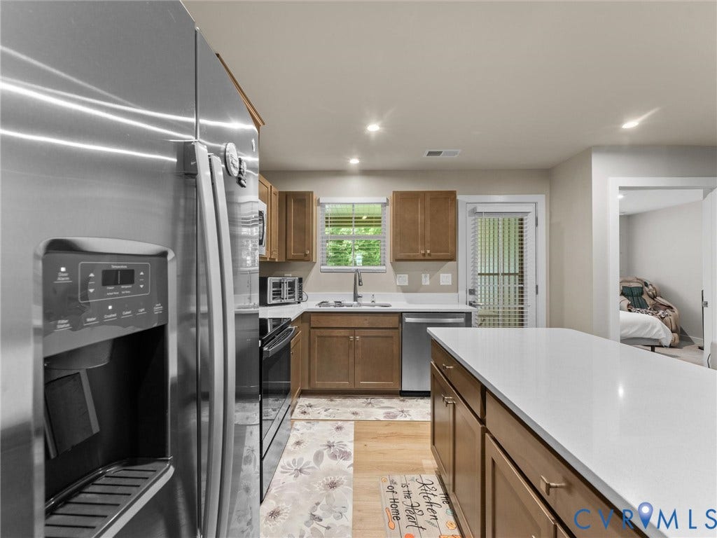 Contemporary kitchen featuring a stainless steel refrigerator, white countertops, built-in cabinetry, recessed lighting, and wood-finish flooring