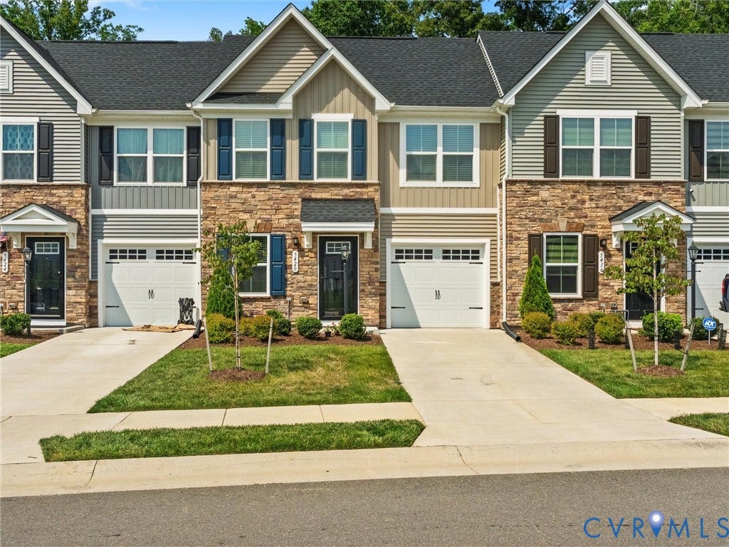 Townhome exterior featuring stone and siding finishes, individual garage, and dedicated driveway