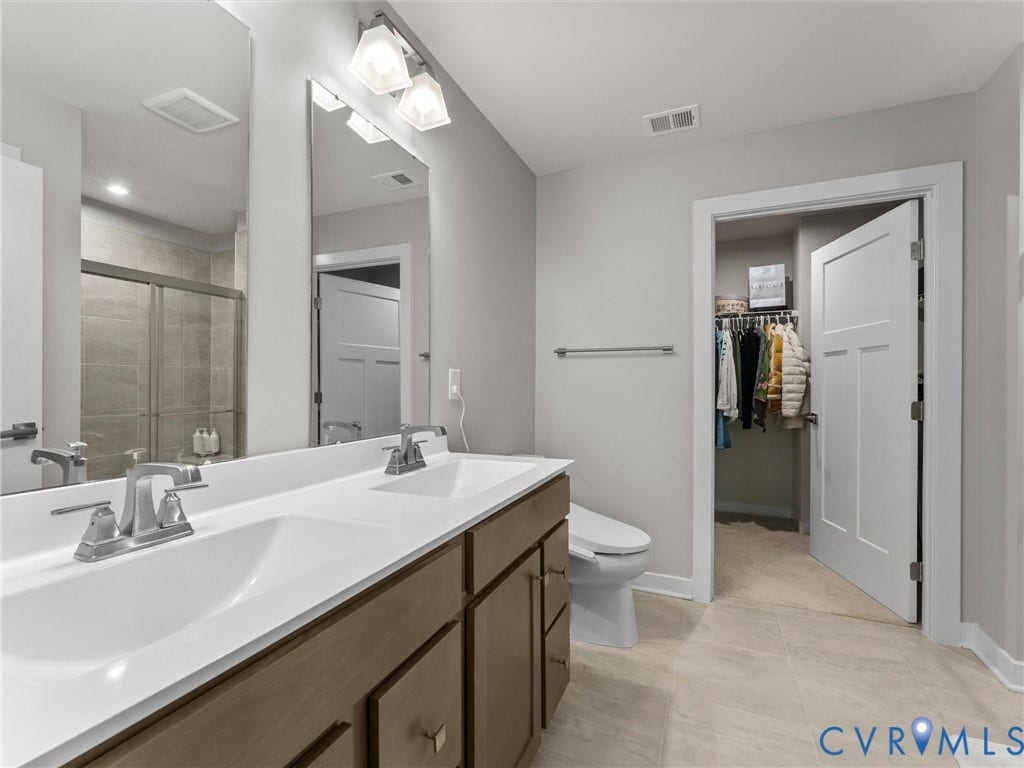 Double vanity with integrated sinks, brushed nickel fixtures, and wood-finish cabinetry
