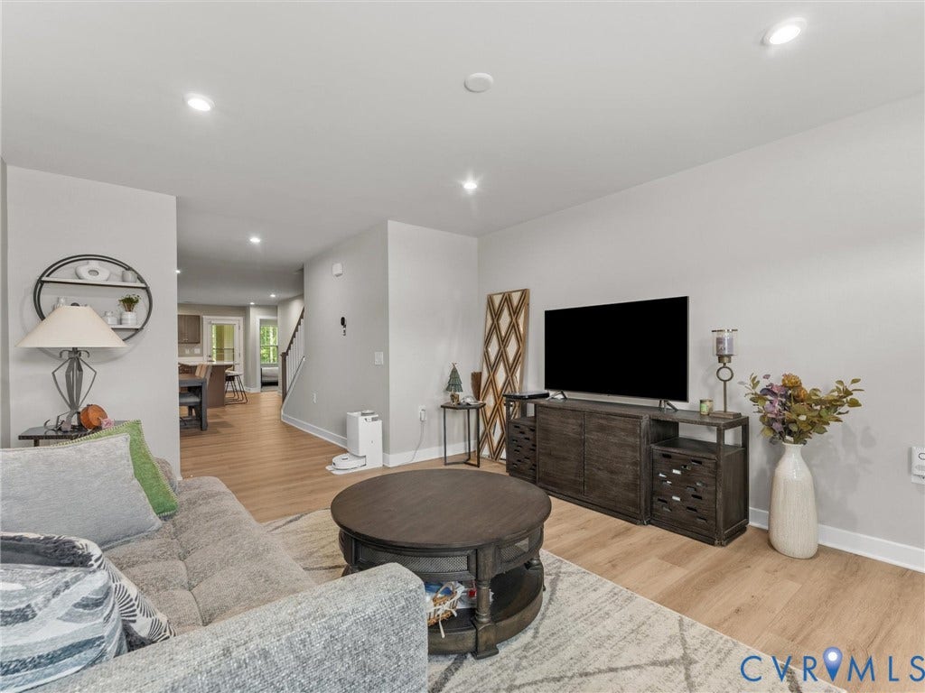 Recessed lighting illuminates the living space with wood-finish flooring