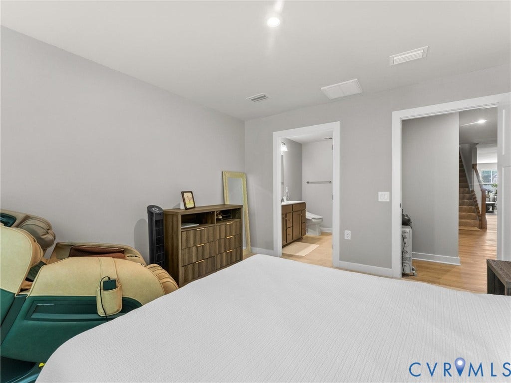 Recessed ceiling lighting, light gray wall paint, wood-finish flooring, white trim, and a full bathroom with a wood vanity