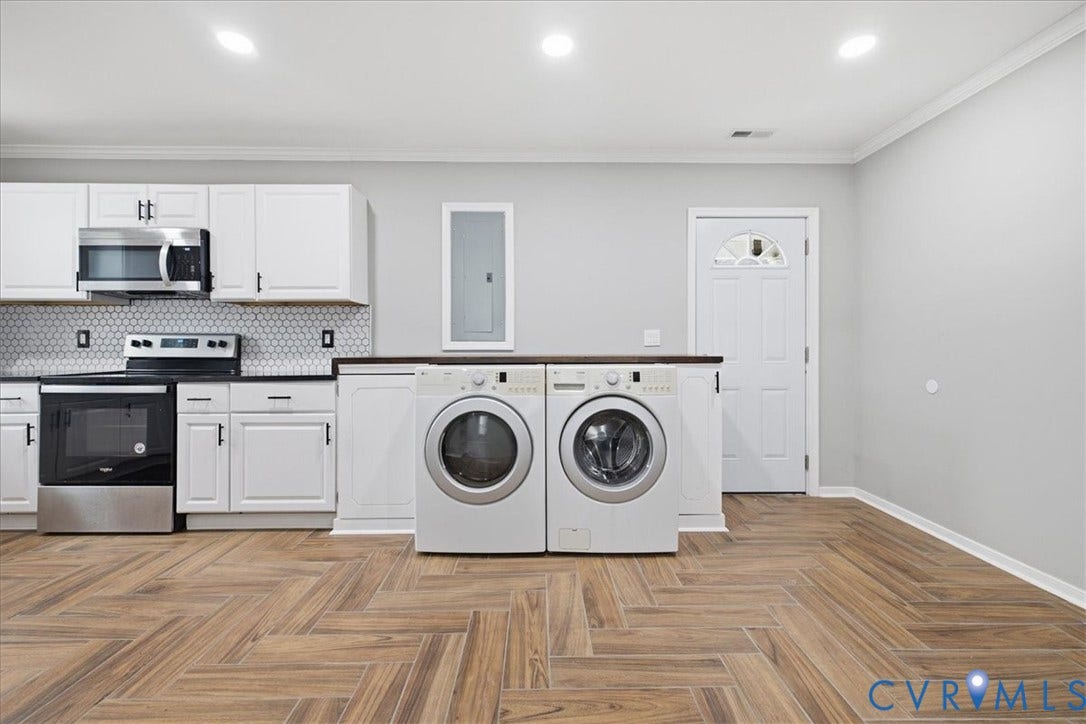 1630 W Washington Street, Petersburg, VA 23803 Wood-finish flooring in a herringbone pattern, recessed lighting, white cabinetry with dark hardware, stainless steel appliances, and a hexagon tile backsplash