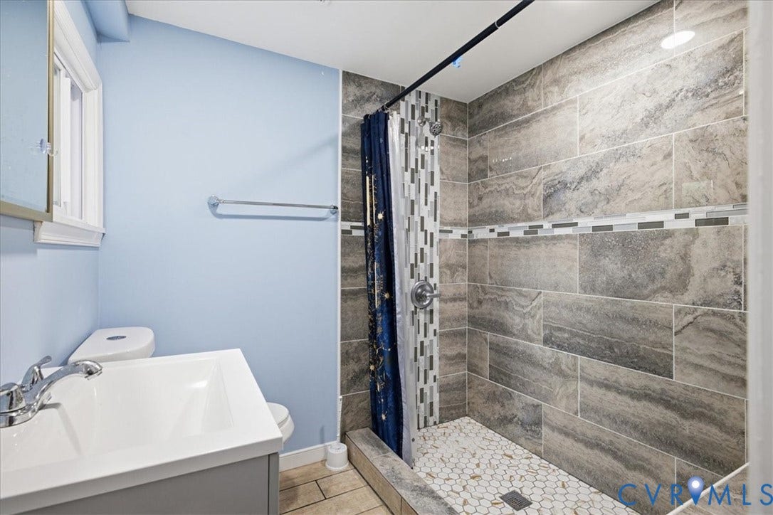 1630 W Washington Street, Petersburg, VA 23803 Walk-in shower featuring large format wall tiles with a decorative mosaic accent and a hexagonal tile floor