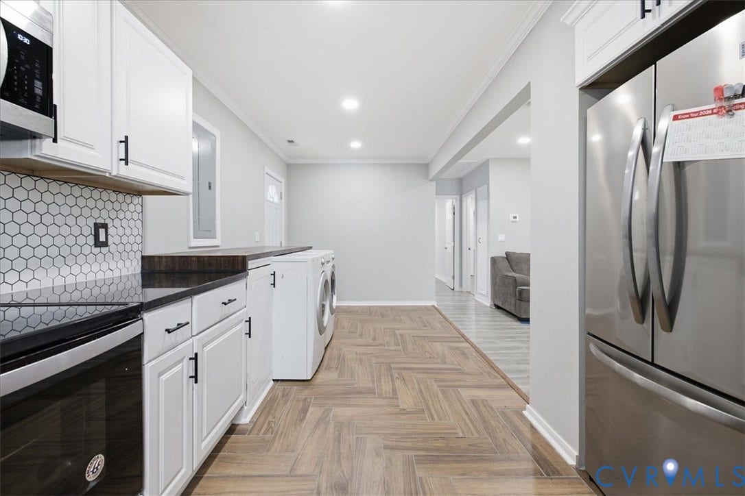 1630 W Washington Street, Petersburg, VA 23803 Herringbone wood-finish flooring, white cabinetry with black hardware, hexagon tile backsplash, stainless steel appliances, and recessed lighting