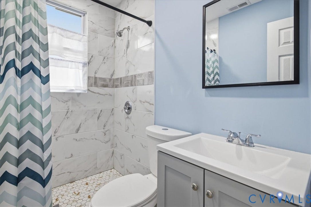 1630 W Washington Street, Petersburg, VA 23803 Shower with white and gray veined tile surround, mosaic tile flooring, and a window
