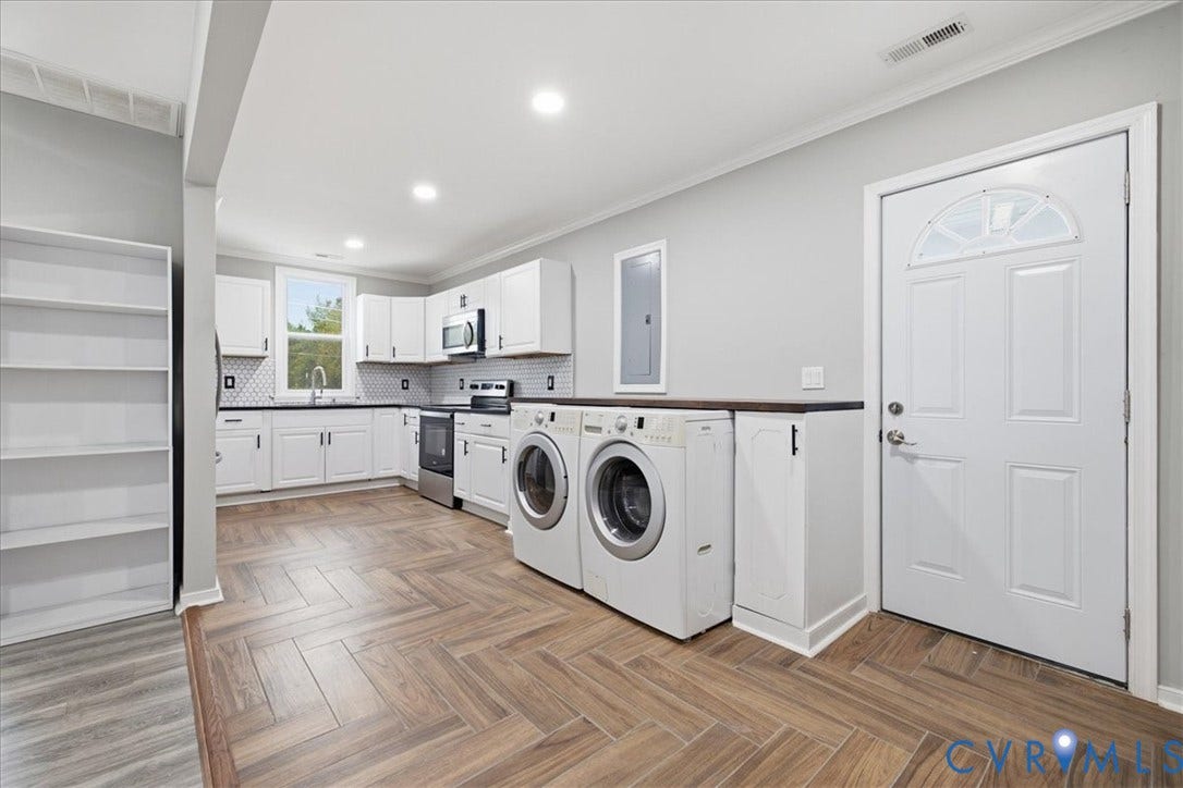 1630 W Washington Street, Petersburg, VA 23803 Herringbone-patterned wood-finish flooring, white cabinetry, dark countertops, white subway tile backsplash, and a white paneled door with an arched glass insert