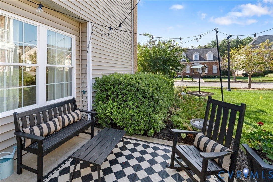 Private outdoor patio featuring a black and white checkerboard surface, string lighting, and direct access to a landscaped garden area