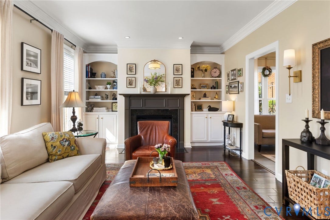 Dark wood-finish flooring, built-in shelving, a fireplace with a dark mantel, and crown molding