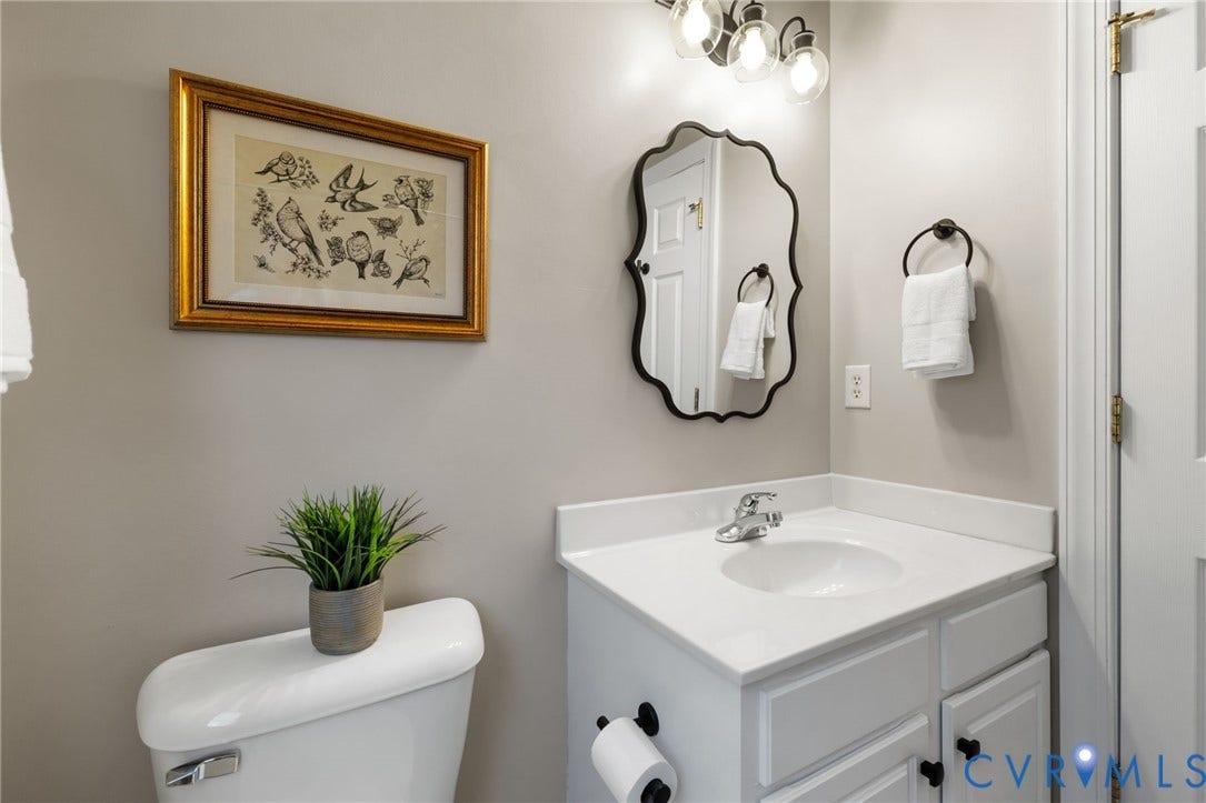 White vanity with integrated sink, chrome faucet, and black cabinet hardware