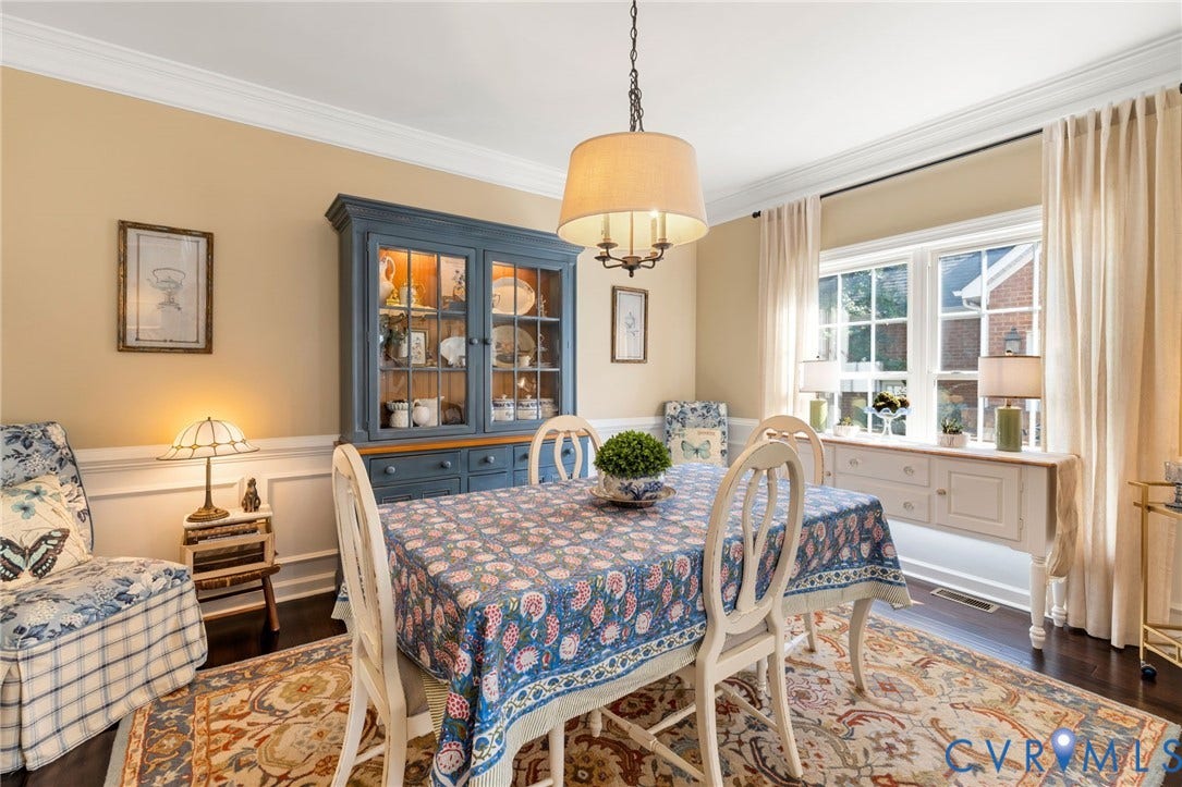 Hardwood flooring, crown molding, built-in display cabinetry, wainscoting, and large windows with architectural grilles