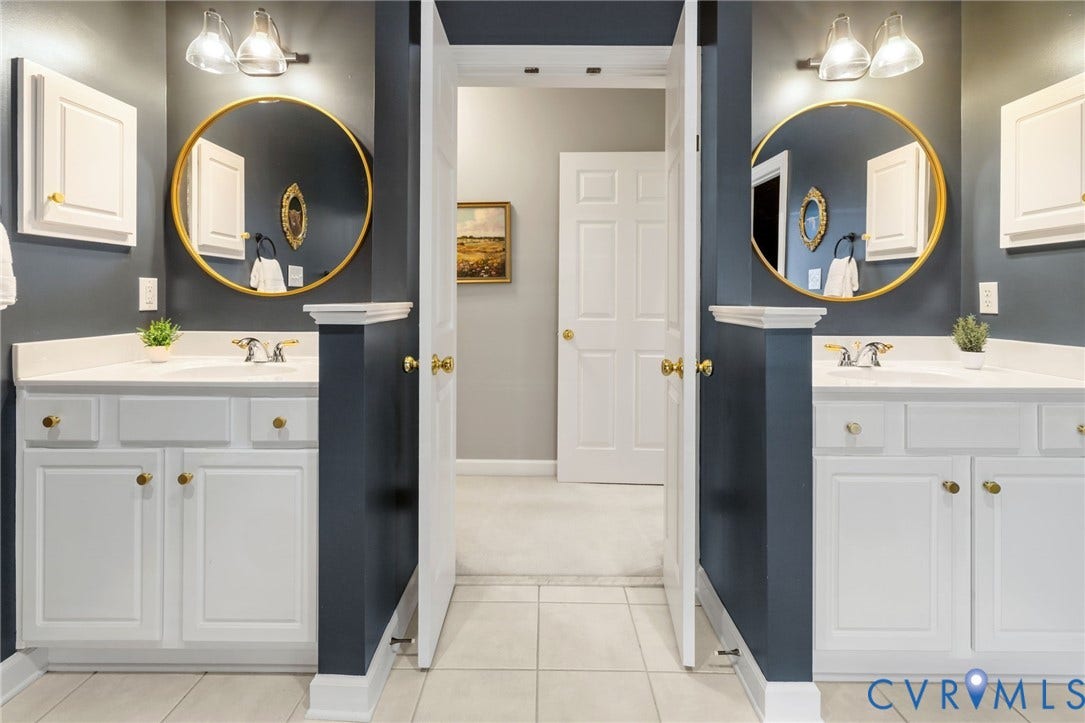 Dual vanity with white cabinetry, gold-toned hardware, round framed mirrors, and wall-mounted light fixtures