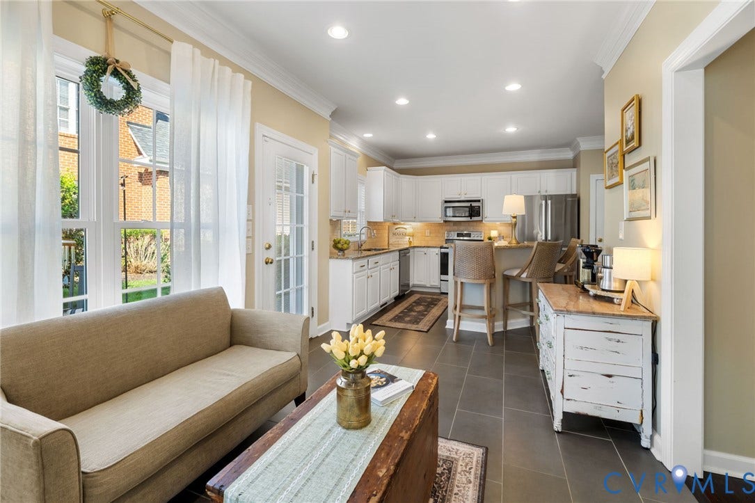 Open-concept living space featuring expansive windows, recessed lighting, crown molding, a kitchen with white cabinetry, and stainless steel appliances