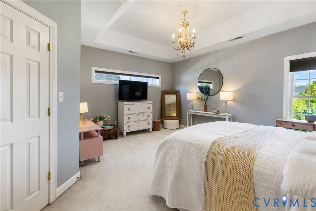 Recessed ceiling with an ornate chandelier, transom window, and a large window with exterior scenery