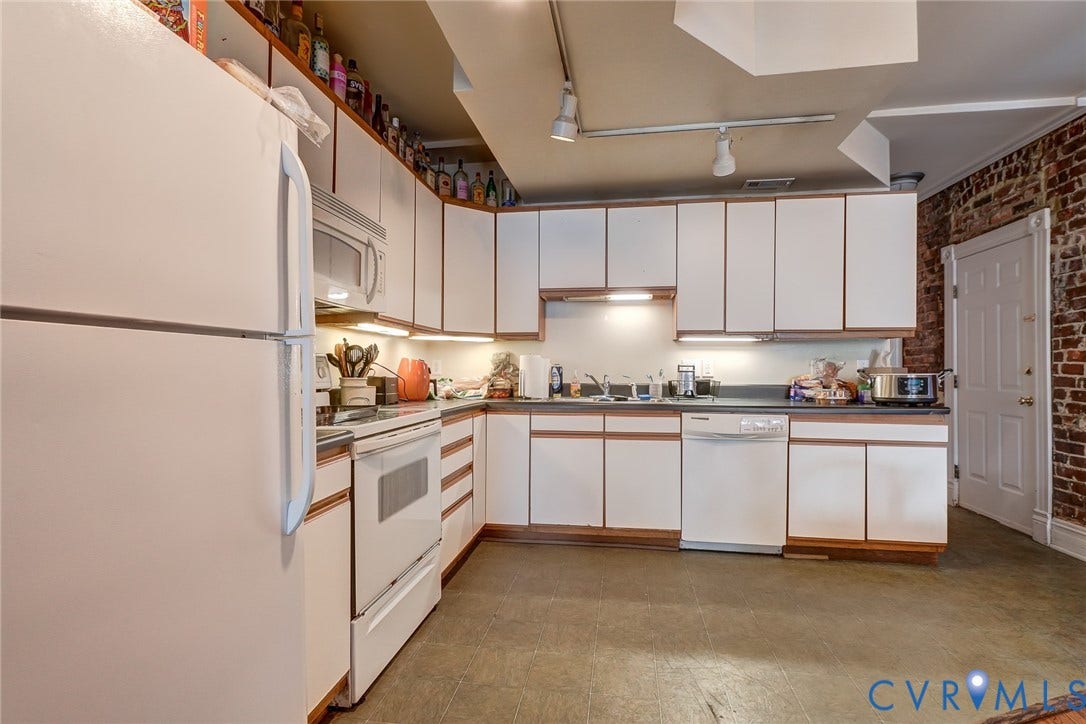 1620 W Cary Street, Fan Extenstion, Richmond, VA 23220 Kitchen featuring white cabinetry with wood trim, track lighting, and exposed brick accents