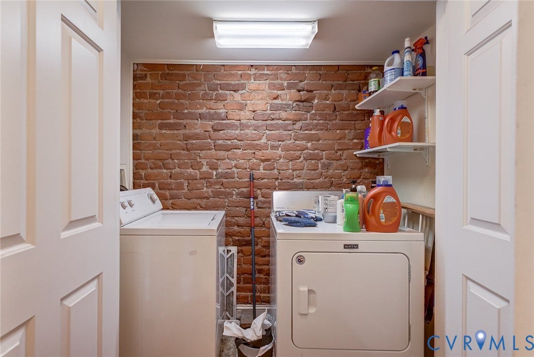 1620 W Cary Street, Fan Extenstion, Richmond, VA 23220 Laundry area featuring a brick accent wall, white paneled doors, built-in shelving, and a ceiling-mounted fluorescent light fixture