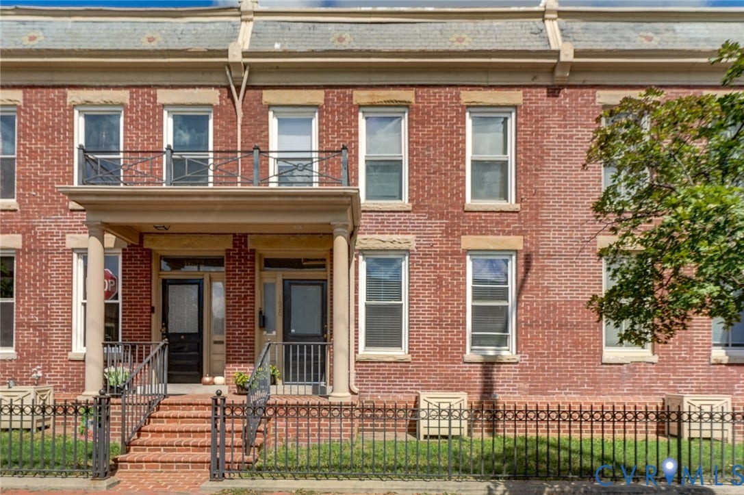 1620 W Cary Street, Fan Extenstion, Richmond, VA 23220 Red brick facade with stone lintels, cornice detailing, a covered porch with round columns, a wrought iron balcony, and a matching wrought iron fence