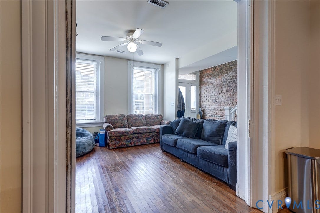 1620 W Cary Street, Fan Extenstion, Richmond, VA 23220 Hardwood flooring, painted walls, exposed brick accent wall, white ceiling fan with integrated lighting, and multiple windows
