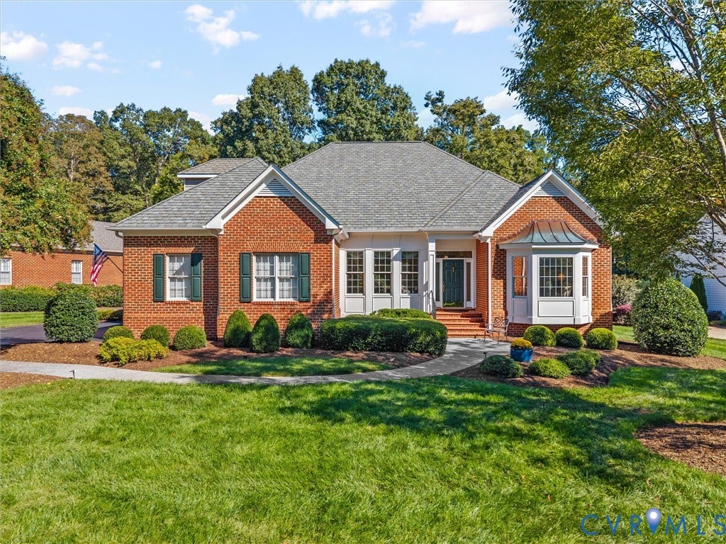 Brick exterior with a gray shingle roof, bay window, and gabled entry
