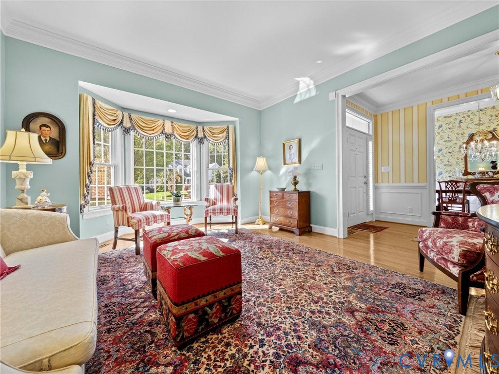 Bay window with multiple panes, hardwood flooring, crown molding, and wainscoting