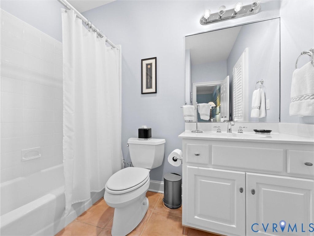 White vanity with a light-colored countertop, chrome fixtures, and a large mirror