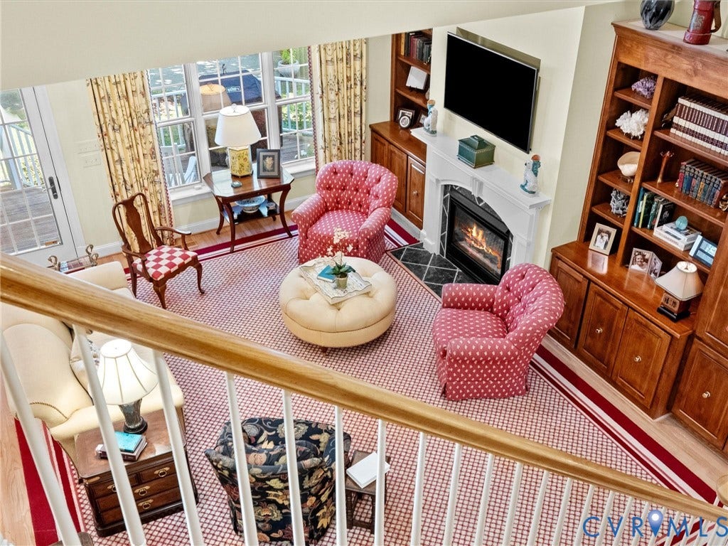 Built-in shelving, rich wood-finish cabinetry, fireplace with decorative mantel, and French doors