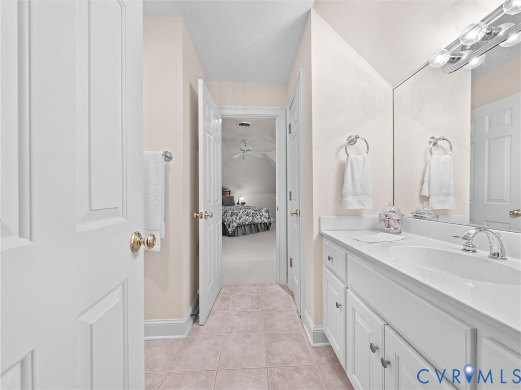 White vanity with integrated sink, chrome faucet, and full-wall mirror