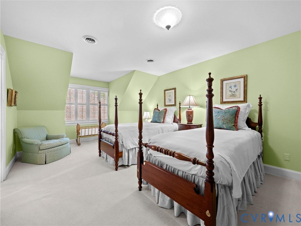 White ceiling fixture, light green wall finishes, light carpeting, window with internal shutters, and white trim