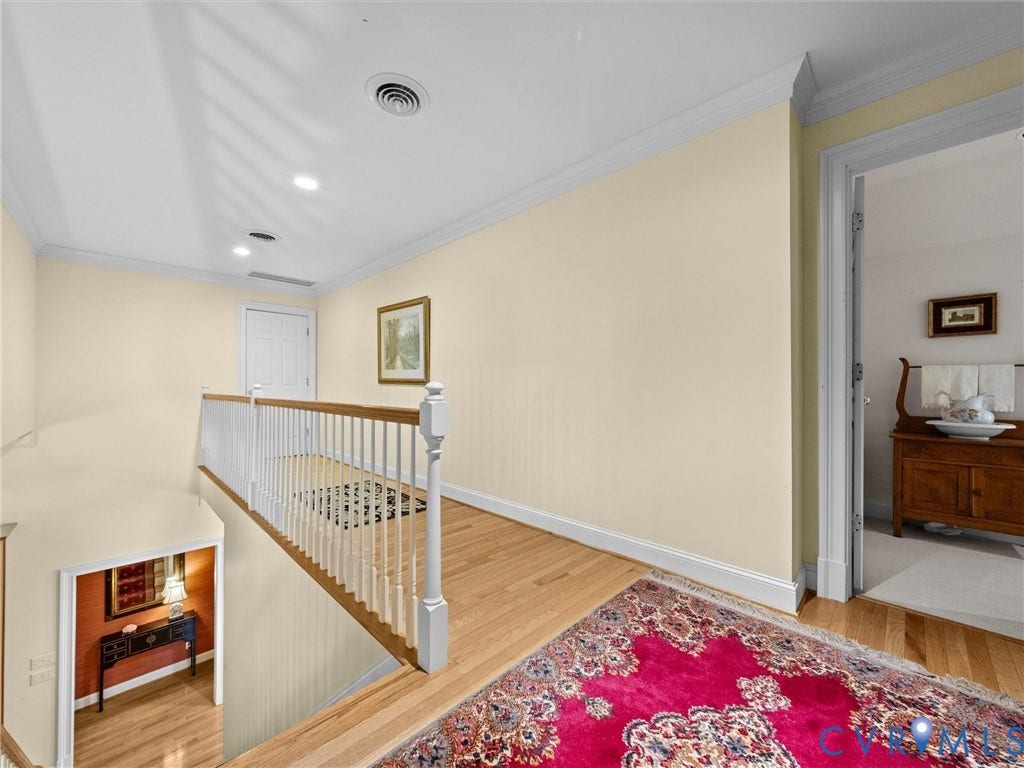 Hardwood flooring, crown molding, recessed lighting, and a white baluster railing with a natural wood top rail