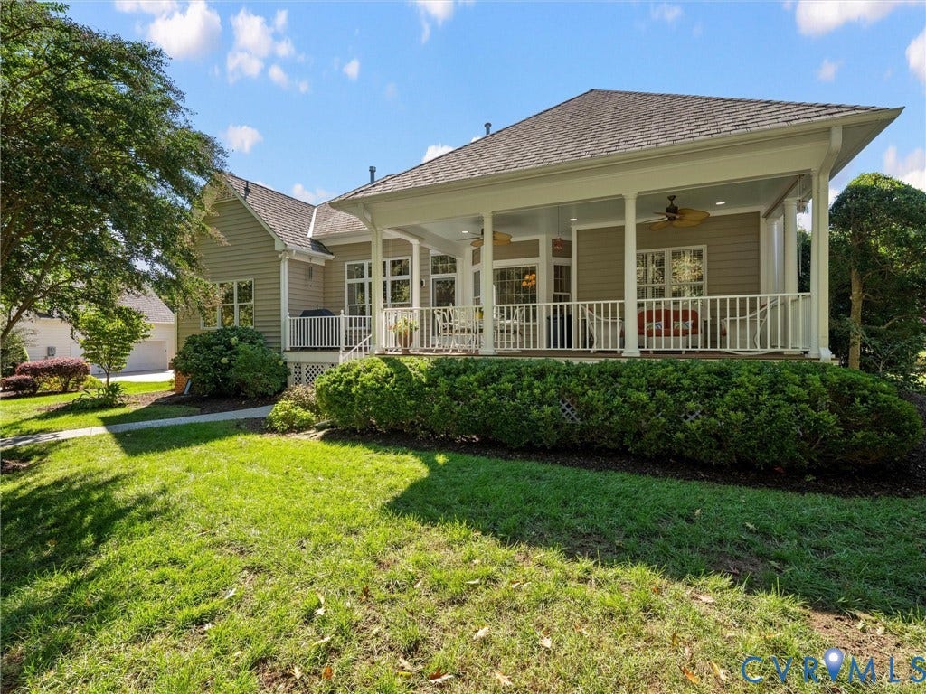 Expansive covered porch with white columns, multiple windows, and a lattice foundation skirt