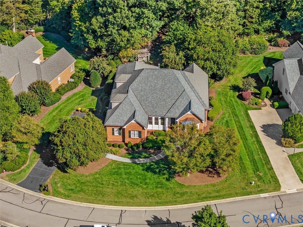 Traditional brick facade with a multi-gabled roofline, mature landscaping, and an asphalt driveway