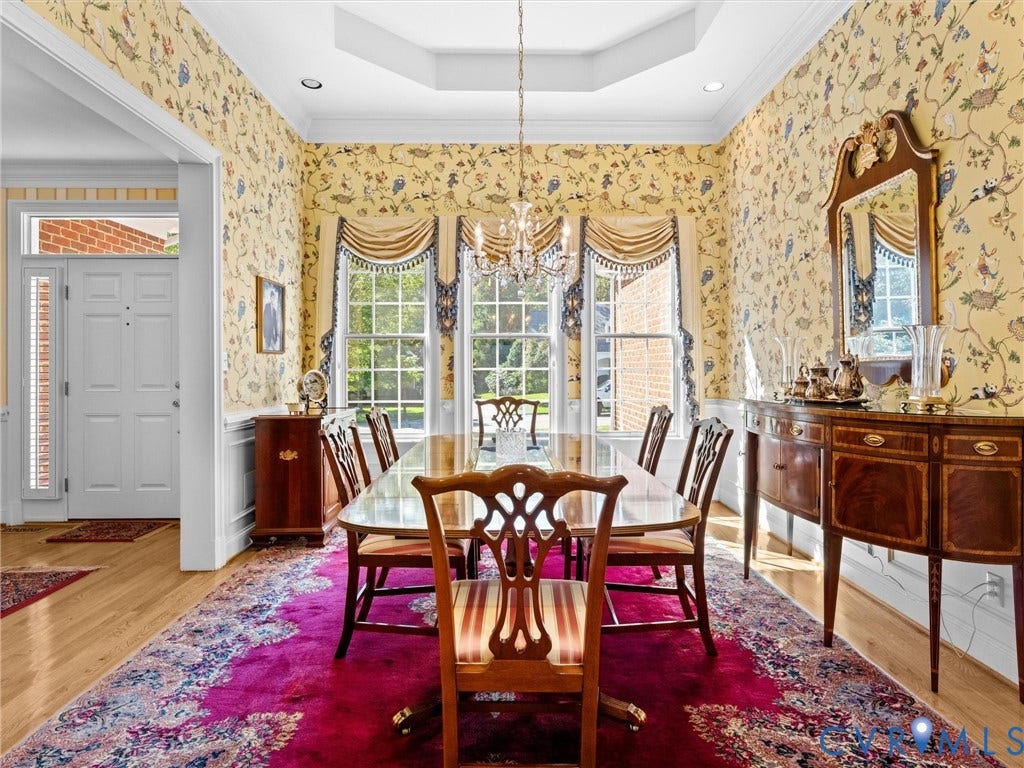 Recessed lighting, ornate chandelier, tray ceiling, hardwood flooring, and multiple large windows